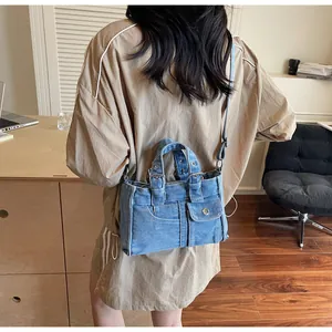 Sac bandoulière en jean bleu avec poches utilitaires porté par un mannequin chic