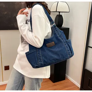 Close-up of deep blue denim tote bag side pockets and leather label detail
