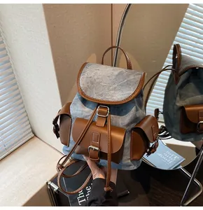 Detail of blue denim canvas backpack with brown leather flaps and buckle pockets