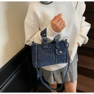 Détail du sac hobo en jean bleu avec poches moto vintage et boucles argentées