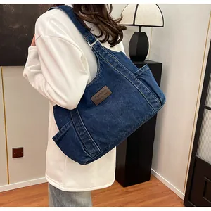 Detailed view of the dark blue denim tote bag with brown leather label and twill texture