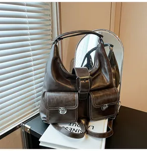 Detail of dark brown vintage faux leather shoulder bag with dual buckle front pockets