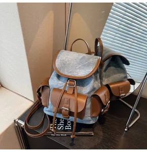 Detail of blue denim and brown leather patchwork backpack with metal buckle closures