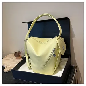 Detail view of a yellow geometric backpack featuring metal zippers in a gift box