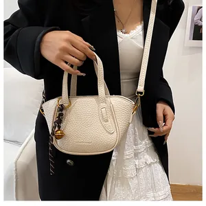 Detail der cremeweißen Eimer-Handtasche aus Leder mit geflochtenem Anhänger-Detail