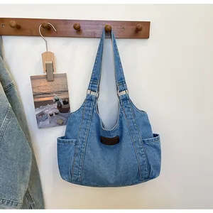 Detail of blue denim tote bag with brown leather label and side pockets on a hook