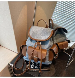 Detail of blue denim bucket backpack with brown leather trim reflected in a mirror
