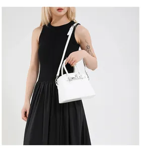 Chic white shell-shaped handbag with silver hardware shown on a black dress for style