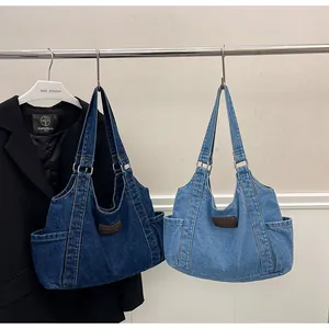 Detail of denim tote bags in dark and mid-blue with leather patch and side pockets