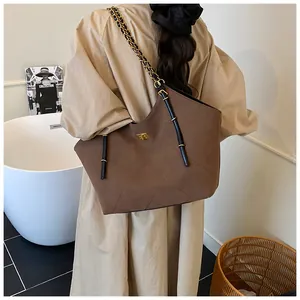 Detail of a large brown suede tote bag with quilted pattern and gold chain strap