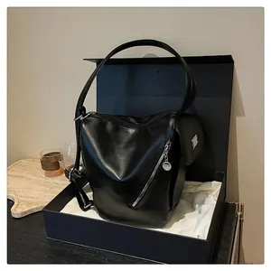 Detail of a black leather shoulder bag with silver zippers on a premium gift box