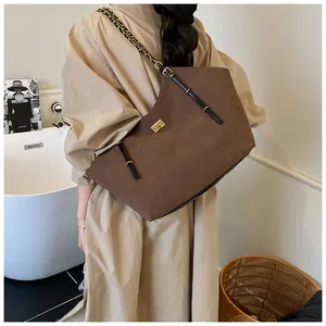 Detail of a large brown quilted tote bag with gold twist lock and chain strap