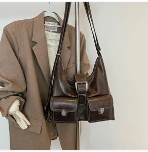 Detail of dark brown retro hobo bag featuring contrast stitching and metal buckle pockets
