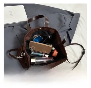 Top view of spacious brown suede handbag interior with organized personal items