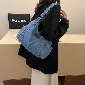 Large denim tote bag in light blue wash with side pocket and vintage brown leather patch