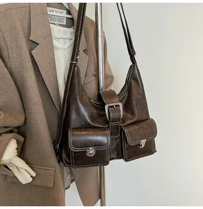 Macro view of vintage brown leather hobo bag with front pockets and metal buckle details