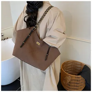 Close-up of brown suede tote bag with quilted diamond pattern and chain strap detail