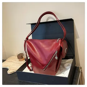 Detail view of burgundy leather shoulder bag with silver zippers in a premium gift box
