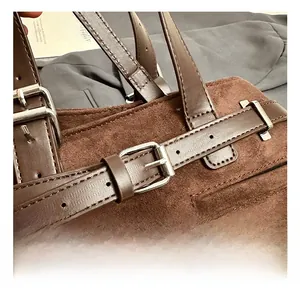 Macro shot of brown suede texture with silver buckle and stitching on a tote bag