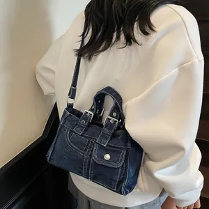 Sac à bandoulière en denim bleu foncé délavé avec surpiqûres porté par un mannequin