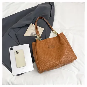 Detail of woven texture tote bag with leather handles and gold chain accents
