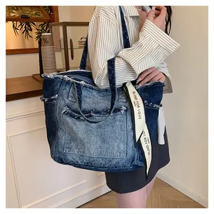Détail des bords effilochés et du ruban décoratif sur un grand sac en denim