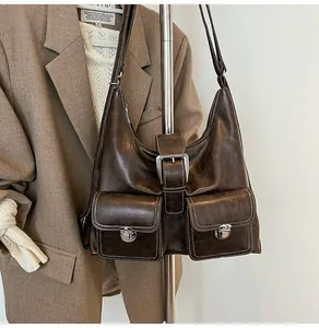 Detail of retro dark brown leather tote with white contrast stitching and metal buckles