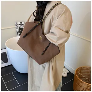 Detailed close-up of dark brown quilted tote bag with gold chain strap and metal lock