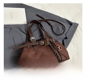 Detail of dark brown suede handbag with metal buckle and woven rope accessory