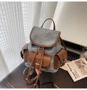 Detail view of retro denim and leather backpack showing the multi-pocket bucket structure