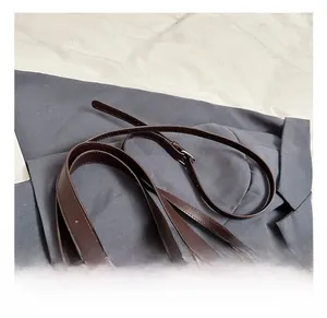 Detail view of brown matte tote with leather handle and chocolate-shaped charm
