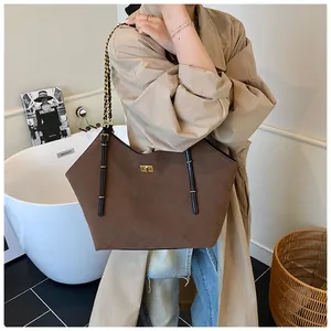 Detail of brown quilted tote bag featuring gold twist lock and chain leather straps