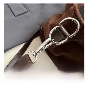 Macro shot of polished silver metal hook and premium leather strap on a suede handbag