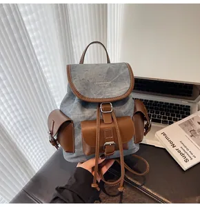 Detail of blue denim and brown leather vintage backpack with metal buckle and logo