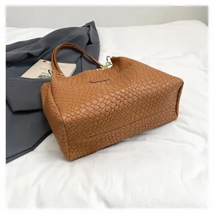 Detail of brown woven tote bag showing dense texture and gold metal hardware accents