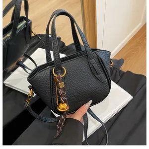 Detail der schwarzen Handtasche aus Narbenleder mit goldener Hardware und Logo-Anhänger