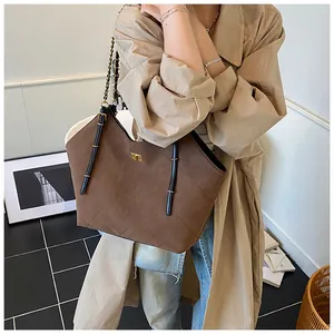 Detail of a large brown quilted tote bag with chain strap and premium suede texture