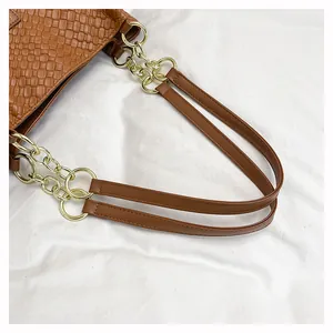 Close-up of brown woven leather tote with golden metal chain and leather strap
