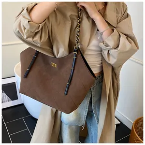 Close-up of brown suede tote bag with diamond quilted pattern and gold metal lock