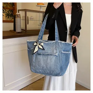 Détail du sac cabas en jean bleu clair avec bords effilochés et foulard en soie au manche