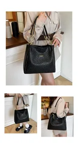 Detail of black woven texture tote bag featuring a gold metal nameplate and chain strap