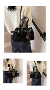 Detail of black matte handbag with belt strap, logo charm and striped silk scarf