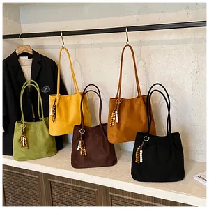 Detail view of four velvet suede tote bags in green, yellow, brown, and black colors