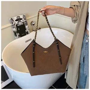 Close-up of brown quilted tote bag with metal chain strap and gold twist lock