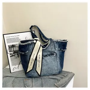 Détail du cabas en denim contrasté avec bords effilochés et foulard en satin décoratif