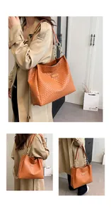Detail of woven brown tote bag with metal chain strap and luxury leather texture