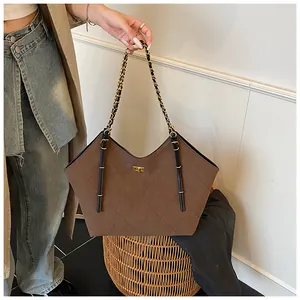 Detail view of brown quilted suede tote bag featuring a gold clasp and chain strap
