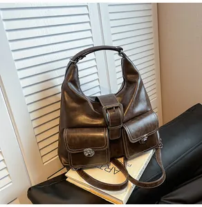 Detailed close-up of brown hobo bag featuring silver buckles and white contrast stitching