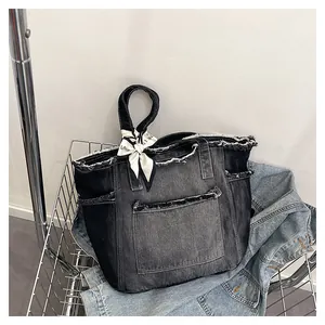 Détail macro du sac cabas en jean noir délavé avec bords effilochés et foulard en soie