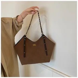 Detail of dark brown tote with large diamond stitching and gold metal twist lock